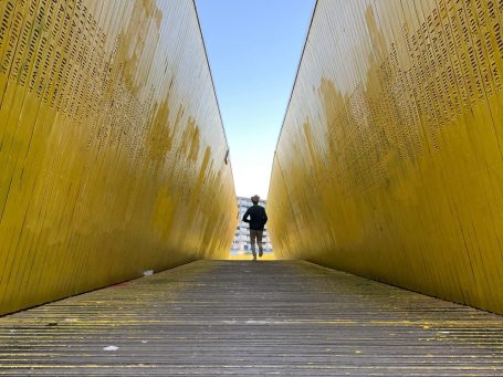 Brücke mit gelben Wänden und junger Mann, der rennt.