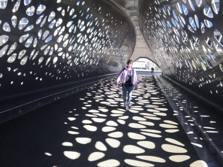 Eine Person läuft durch einen modernen Tunnel mit lochmusterigem Design.